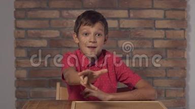 坐在书桌前的孩子拿着一张挂图，在背景红砖墙上刻着字母。